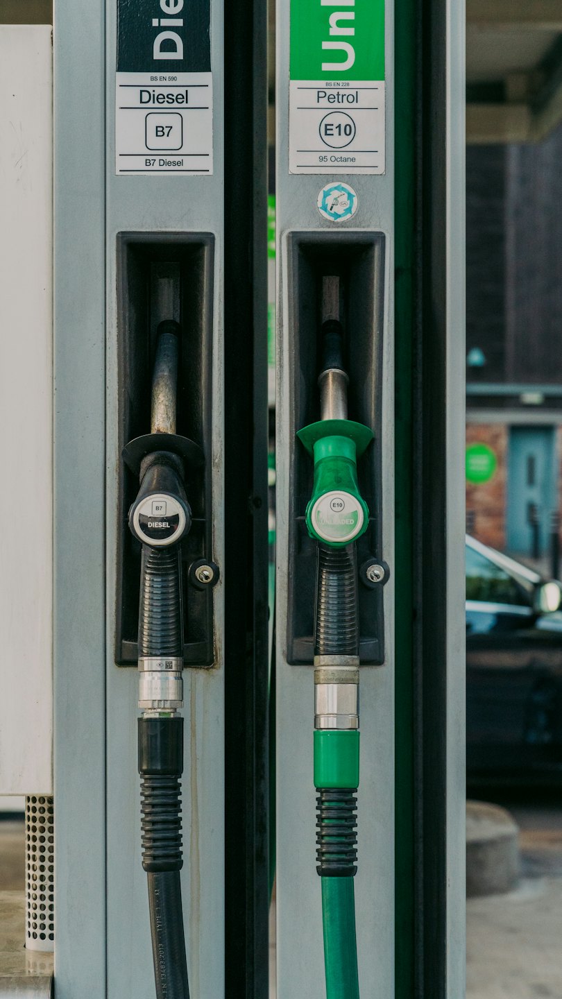 Two fuel pump nozzles labeled diesel and petrol hanging at station.