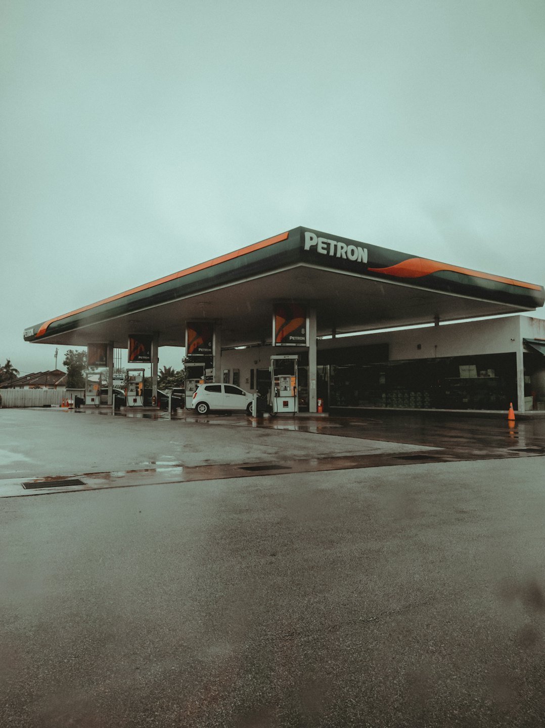 White car parked at a gas station fuel pump.