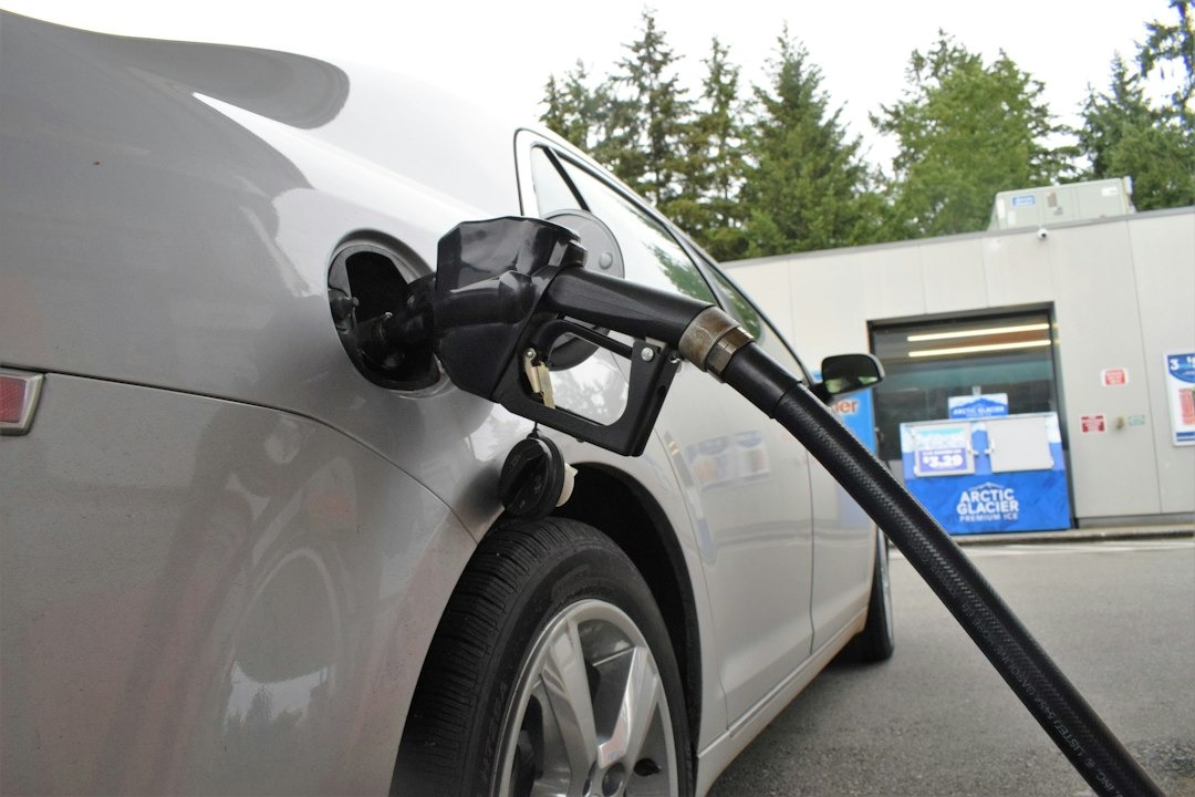 Silver car being refueled at a gas station.